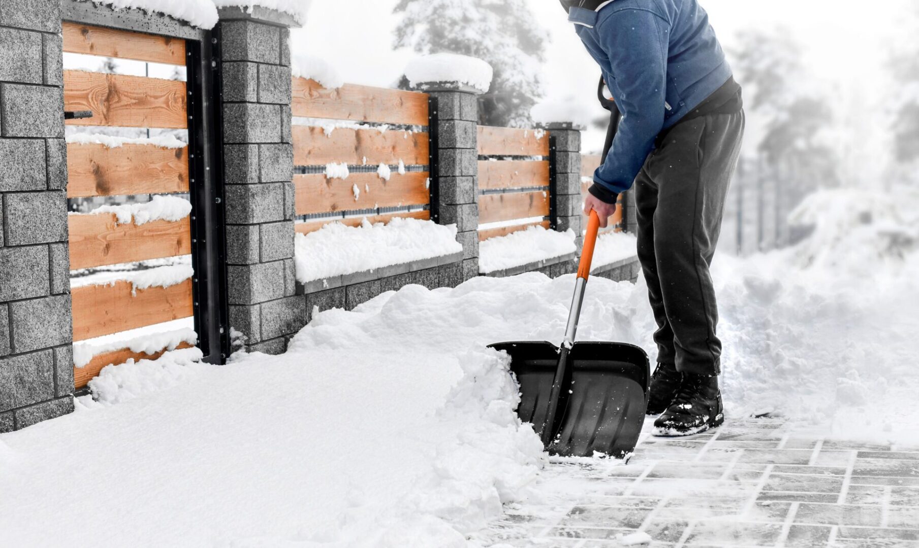 Man cleaning snow from street in winter with shovel after snowstorm.